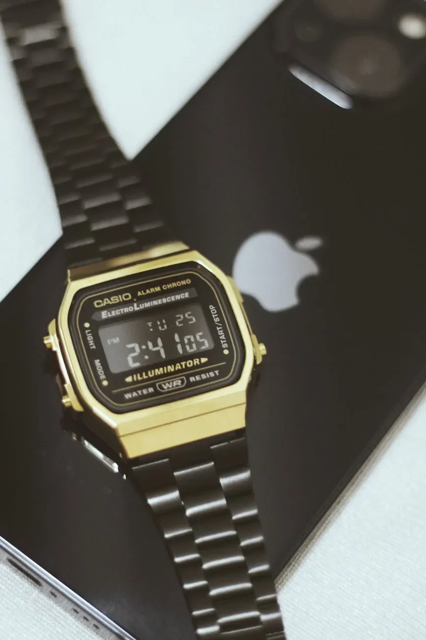 Casio de la línea Vintage dorado con correa de acero negra, apoyado sobre un teléfono