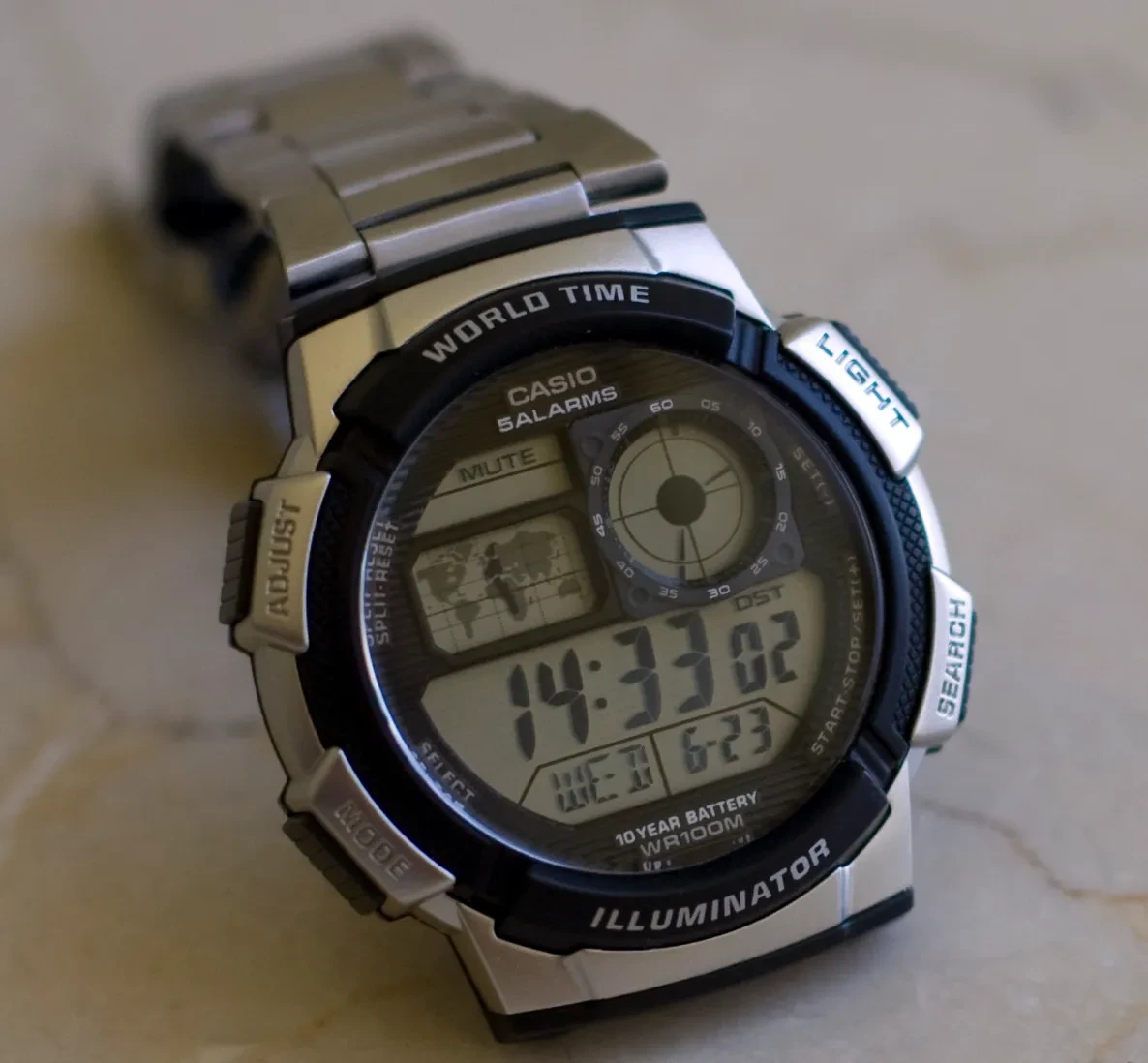 Casio AE-1000W plateado y negro con el mapa del mundo en una esfera redonda