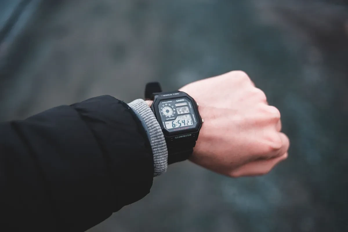 Brazo con un Casio AE-1200 digital negro y la manga de un abrigo oscuro