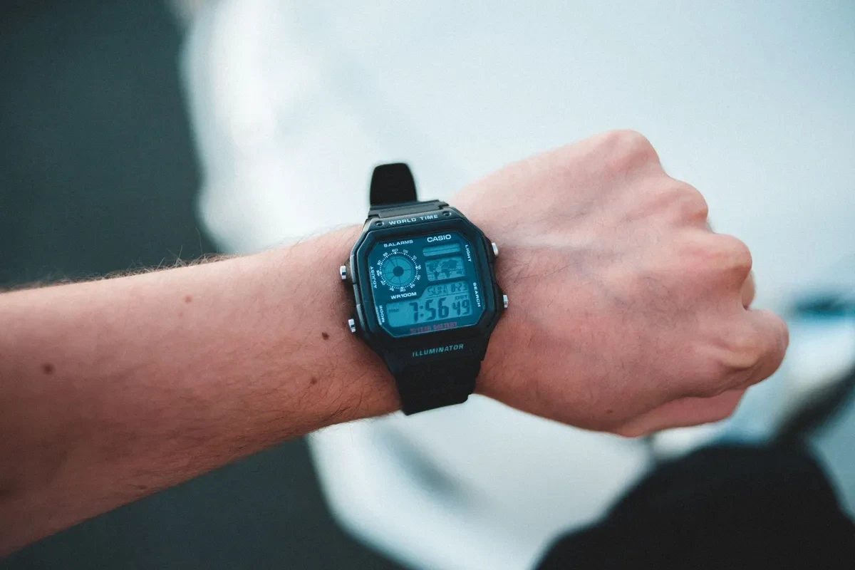 Casio AE-1200 negro en la muñeca de un hombre, con la pantalla iluminada en azul