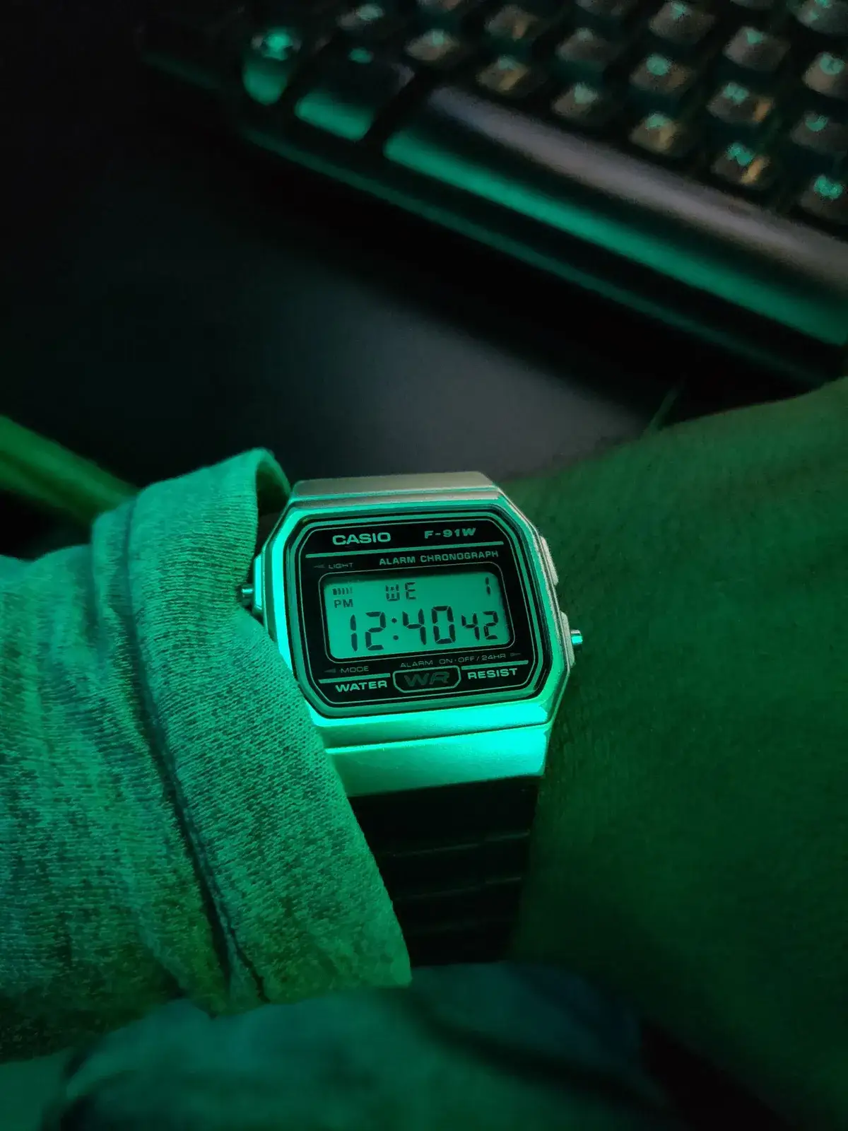 Reloj digital Casio en una muñeca con poca luz, con la pantalla iluminada y verdosa