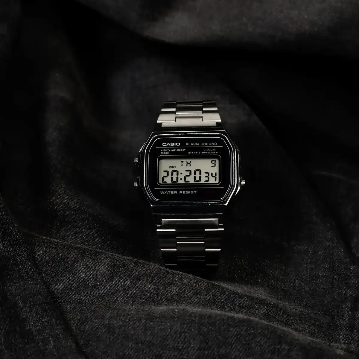 Casio Vintage digital con caja y correa de acero en negro, sobre una tela oscura
