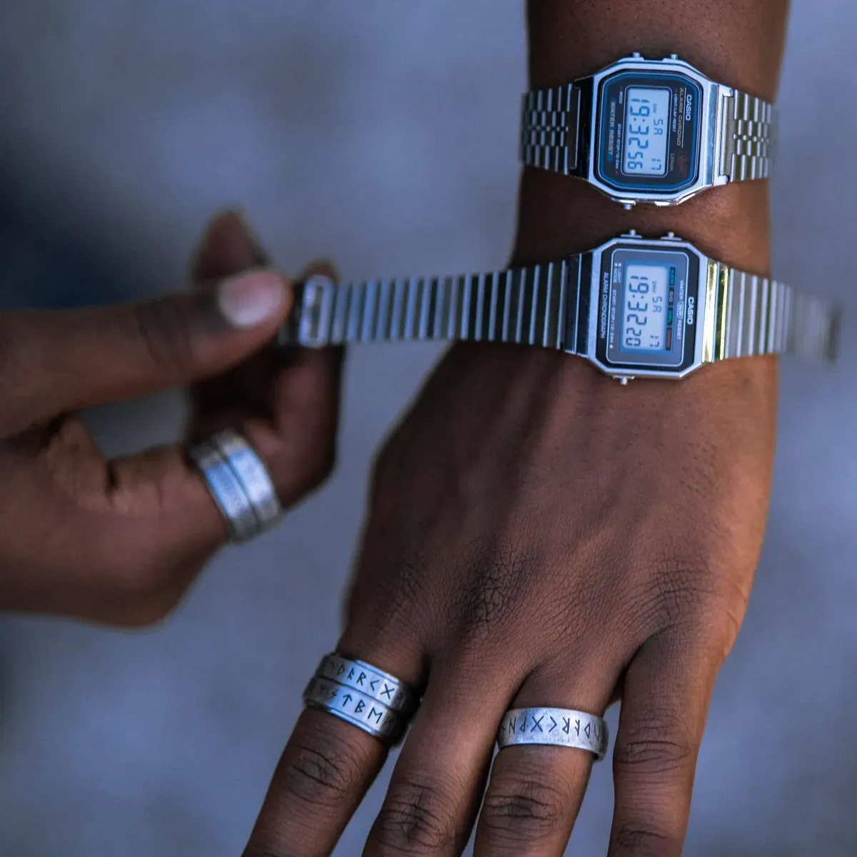 Dos manos con relojes digitales de acero de estilo Casio Vintage y anillos plateados