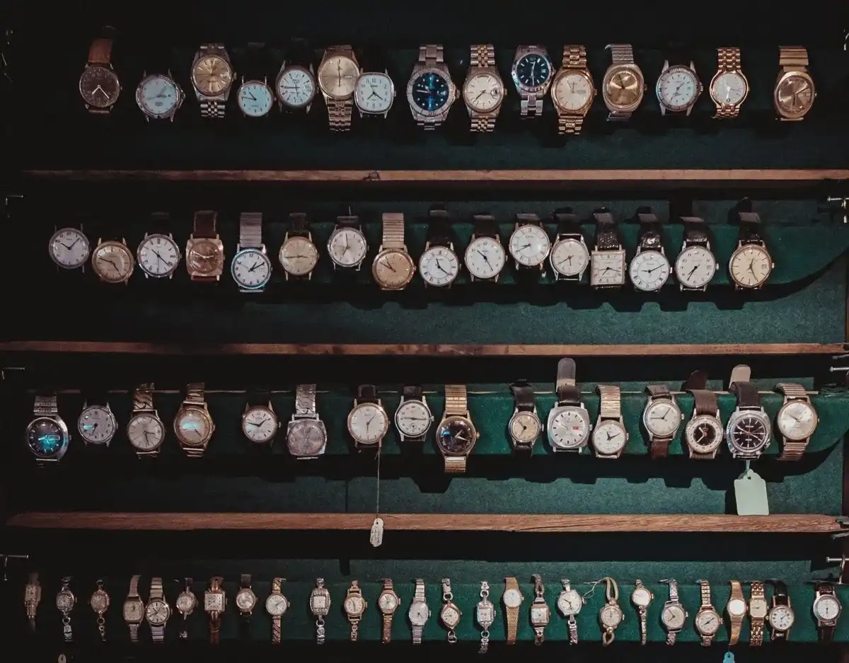 Estanterías de madera oscura con decenas de relojes de pulsera antiguos expuestos en fila