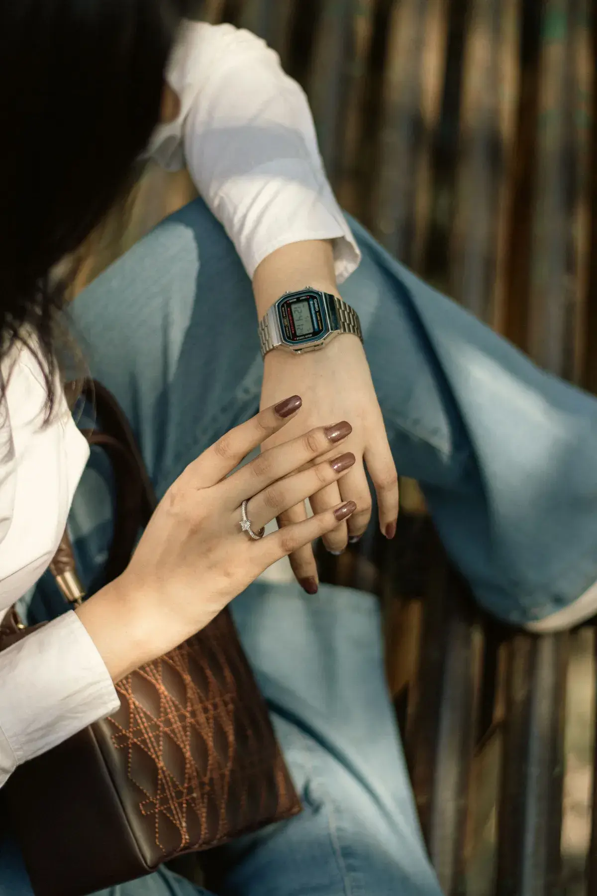 Mujer sentada con un reloj digital de correa de acero en la muñeca, con los brazos cruzados sobre la rodilla