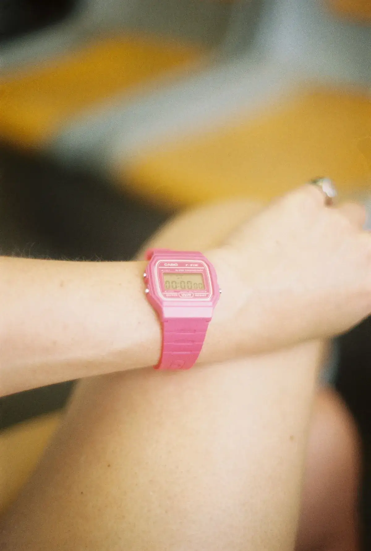 Reloj digital rosa de caja cuadrada en la muñeca de una mujer, a la luz del sol
